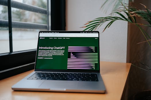 A laptop displaying ChatGPT on a desk by a window, featuring a modern home office setup.